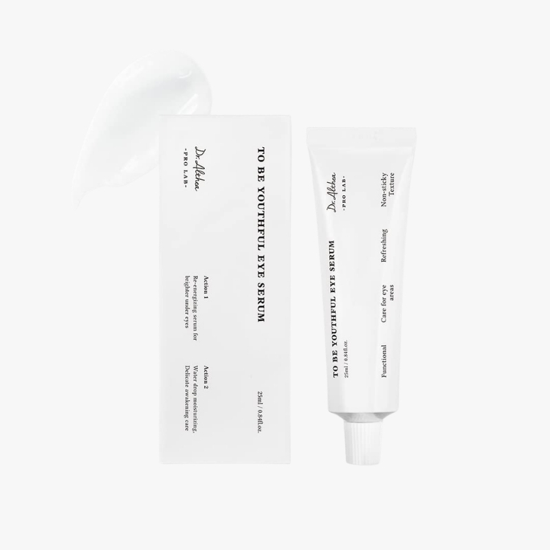 White skincare product set: a tall rectangular box and a squeezable tube labeled Eye Serum, with a white spatula in the background.