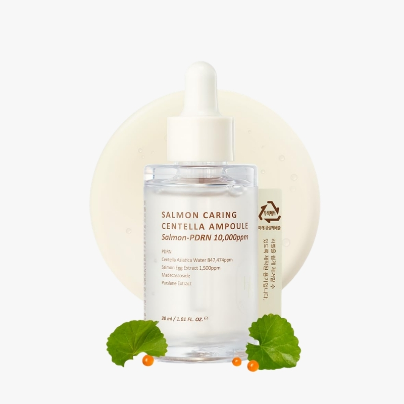 Clear dropper bottle labeled Salmon Caring Centella Ampoule, with a pale circular backdrop and green leaves with small orange berries at the base.