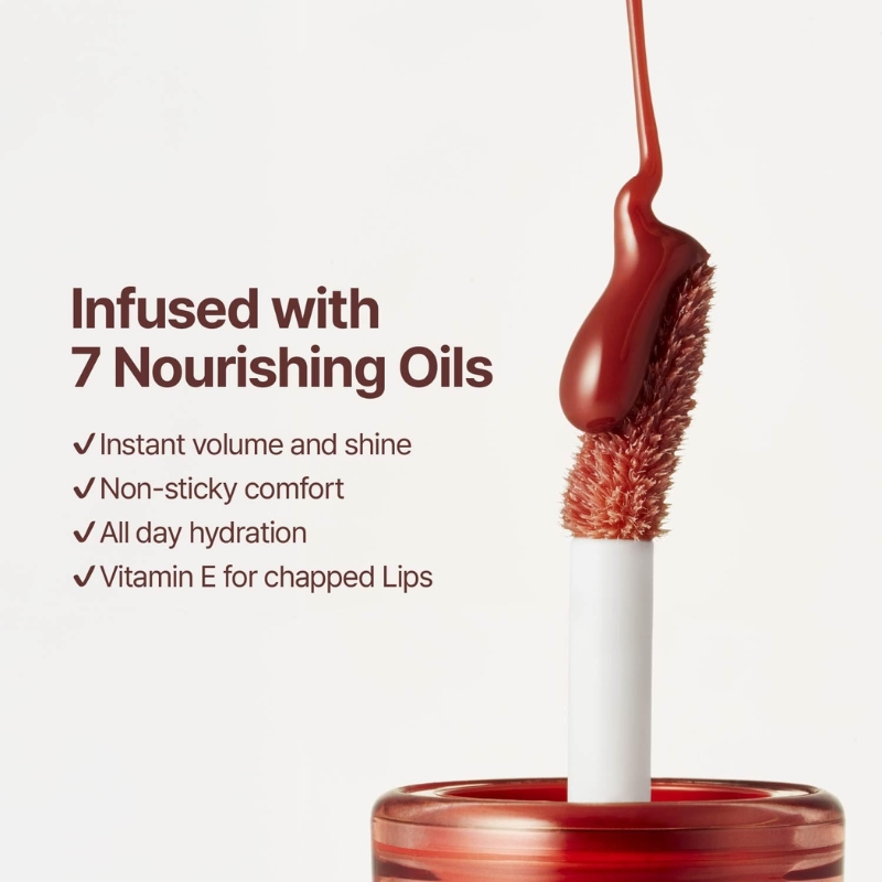 Advertisement for lip gloss infused with 7 nourishing oils; red gloss on a wand with a white stem and bottle.