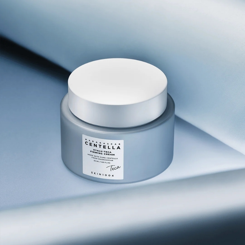 Jar of Centella skin cream with a white lid on a soft blue background.