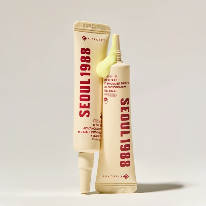 Two beige skincare tubes with bold vertical red lettering reading SEOUL 1988; one tube is open with pale green cream squeezed at the nozzle, on a pale background.