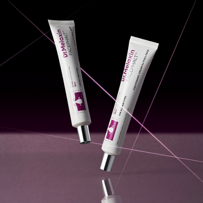 Two white skincare tubes labeled with purple accents float in a dark purple studio backdrop, likely a facial cream product.