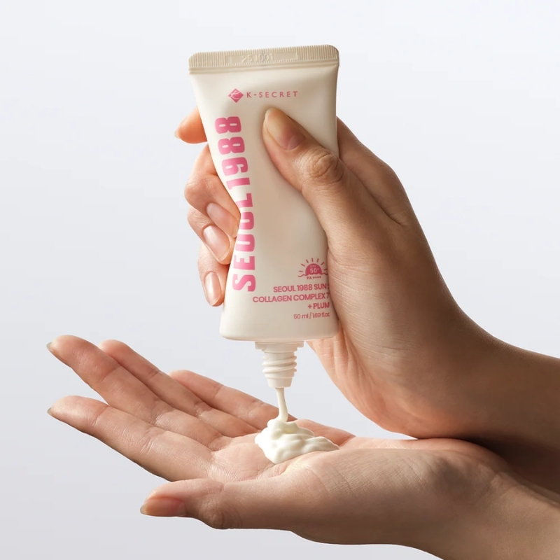 Hand squeezing a small tube of skincare product onto the opposite palm, showing creamy lotion dripping from the nozzle.