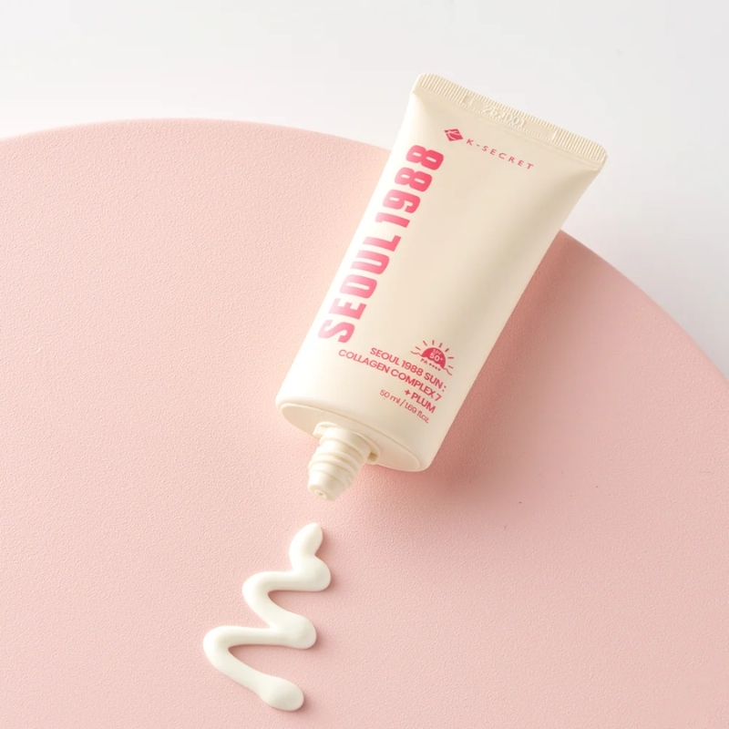 Tube labeled Seoul 1988 Sun cream with cream squiggle on a pink curved surface.