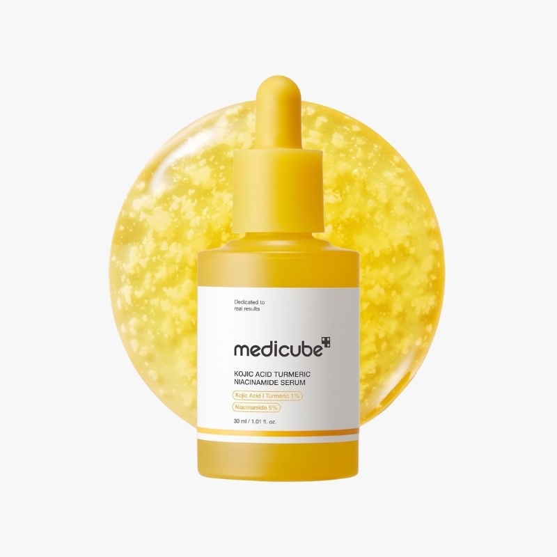 Yellow bottle with dropper containing Medcube Kojic Acid Turmeric Niacinamide Serum, set against a yellow circular backdrop (skincare product).