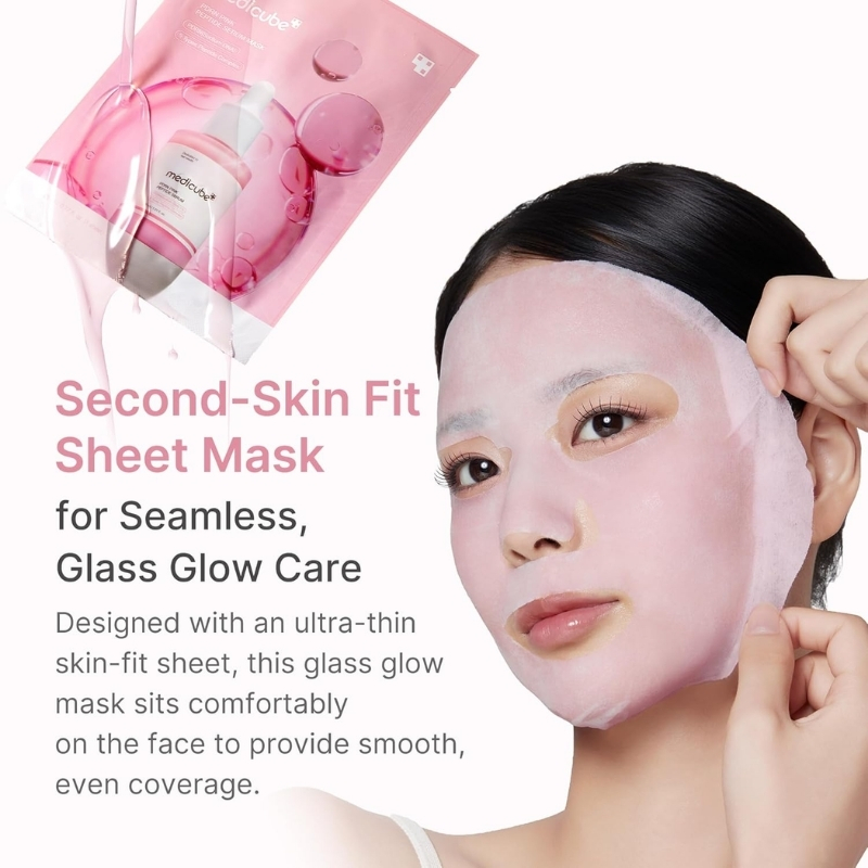 Model applies a pink Second-Skin Fit Sheet Mask on her face; product packaging appears in the top-left corner, promoting glass-glow care.