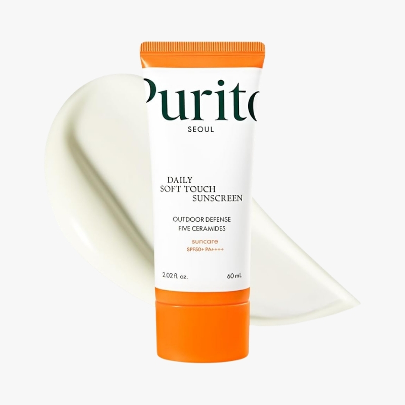 Purito Seoul Daily Soft Touch Sunscreen tube with orange cap and cream smear behind it in white background.