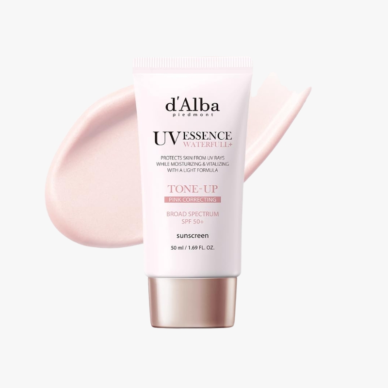 Tube of d’Alba UV Essence sunscreen with pink tone, labeled 'Tone-Up Pink Correcting' and SPF 50+. A swatch of pink cream to the left.